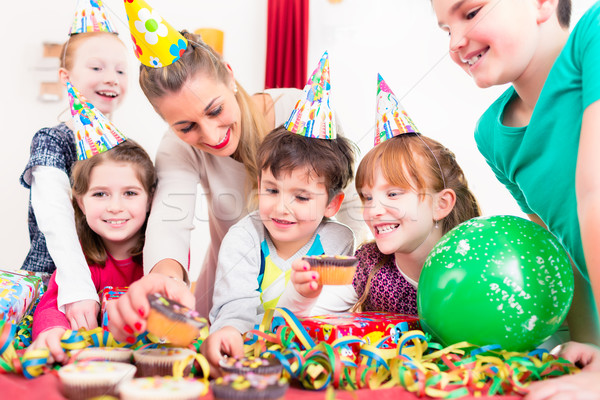 Children at birthday party with muffins and cake Stock photo © Kzenon