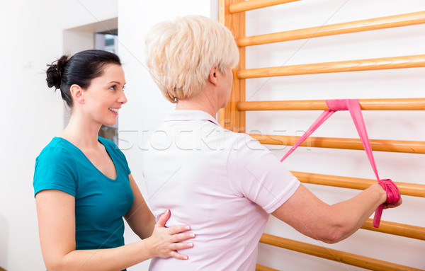 Physio assisting elderly woman during exercise with power band a Stock photo © Kzenon
