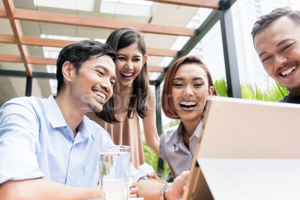 Stock photo: Group of four young Asian people sitting together outdoors at a 