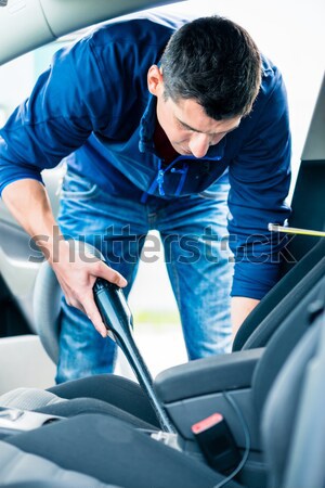Young man using vacuum for cleaning the interior of a car  Stock photo © Kzenon