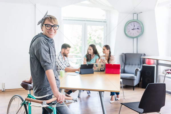 Cheerful young woman holding her commuter bike in a shared office Stock photo © Kzenon