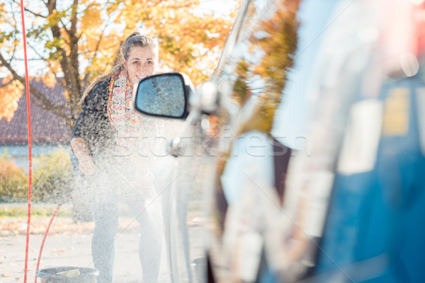 Woman using high pressure nozzle to clean her car Stock photo © Kzenon