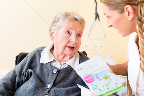 Nurse giving birthday card to senior woman in home Stock photo © Kzenon