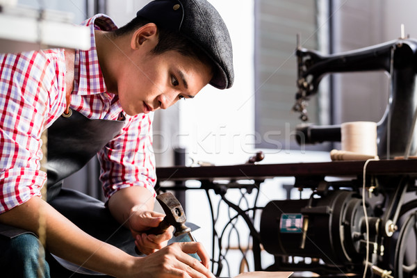 Asian shoe or belt maker in his leather workshop Stock photo © Kzenon