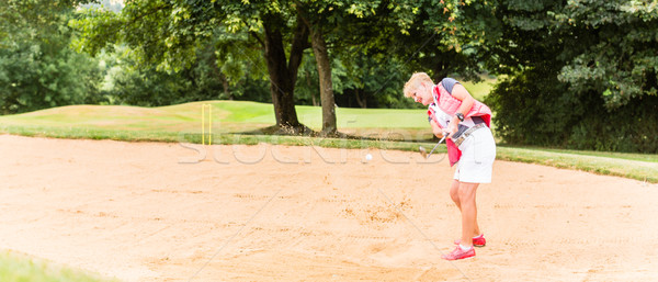 Senior woman at golf having stroke in sand bunker Stock photo © Kzenon