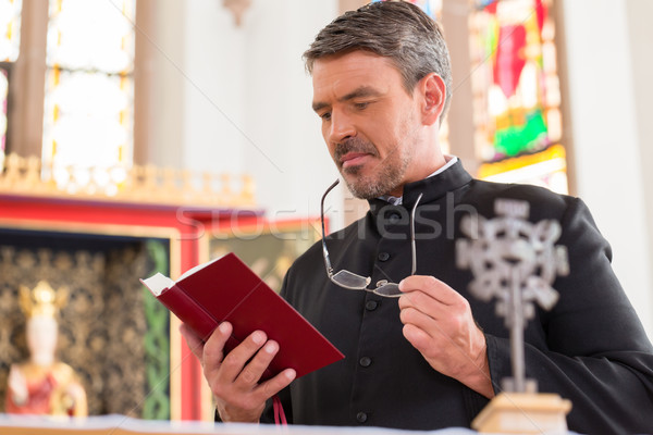 Padre leitura bíblia igreja em pé altar Foto stock © Kzenon