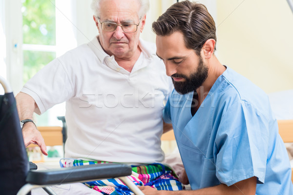 Elderly care nurse helping senior from bed to wheel chair  Stock photo © Kzenon