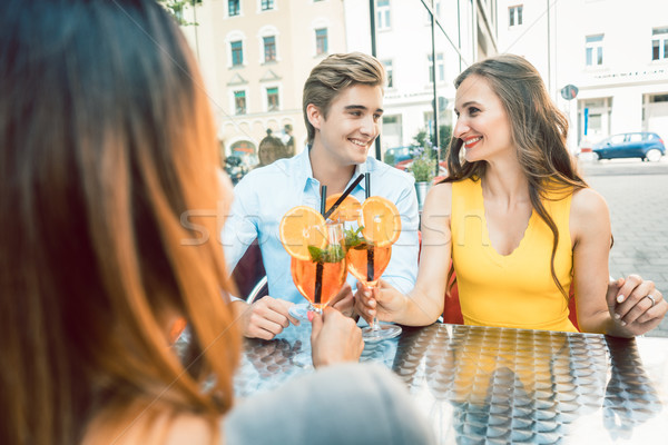Happy couple toasting with their mutual female friend at a trendy restaurant Stock photo © Kzenon