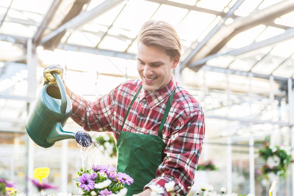 Stock photo: Skilled young man watering houseplants while working as florist 