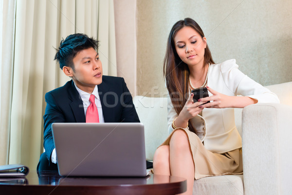 Stock photo: Businesspeople in Asian hotel room with laptop