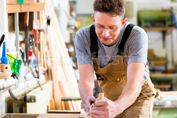 Carpenter with wood planer and workpiece in carpentry Stock photo © Kzenon