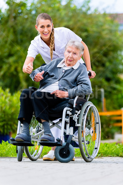 Senior woman in nursing home with nurse in garden Stock photo © Kzenon