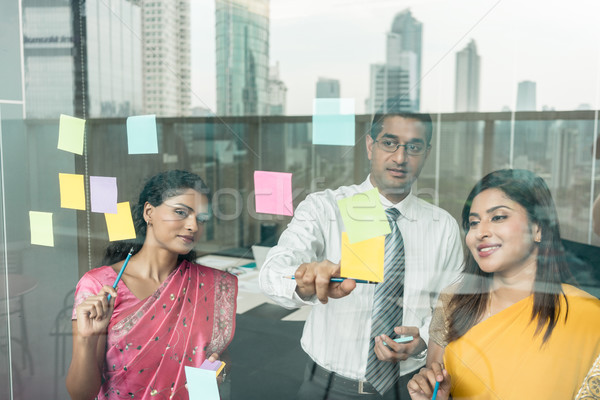 Indian employees sticking reminders on glass wall in the office Stock photo © Kzenon
