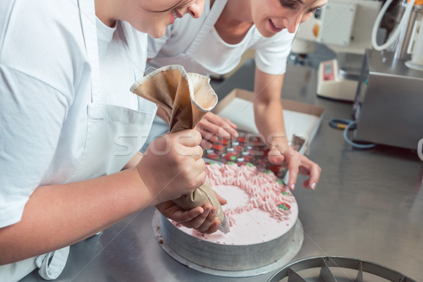 Confectioner women putting cream on cake Stock photo © Kzenon