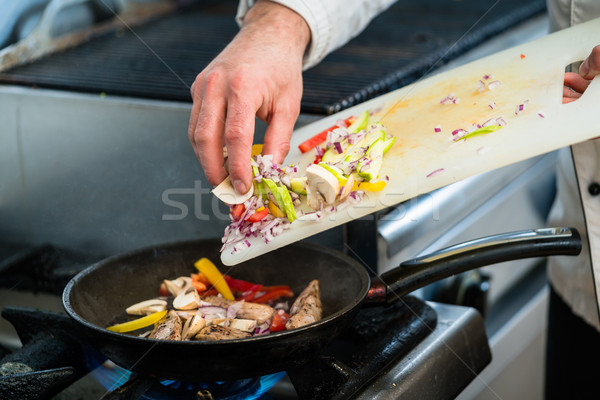 Chef putting ingredients to pan in restaurant kitchen Stock photo © Kzenon