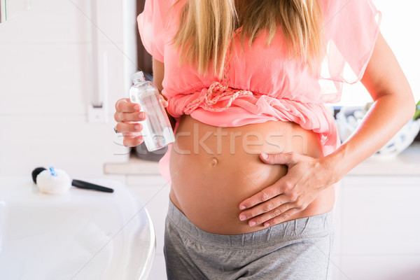 Soon-to-be mum caring for skin at belly Stock photo © Kzenon