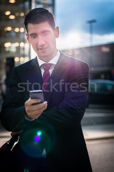 Business man using phone in evening outdoors Stock photo © Kzenon