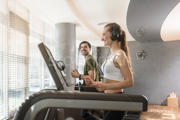 Stock photo: Young woman listening to music while running on a modern treadmill