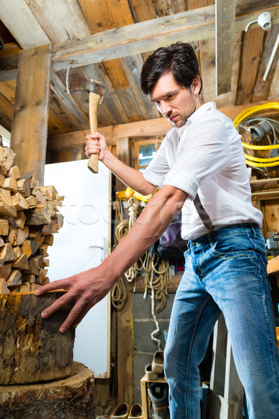 Young man chopping fire wood in mountain chalet Stock photo © Kzenon