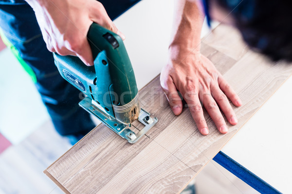 Stock photo: DIY worker cutting wooden panel with jig saw