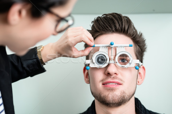 Man with optician at eyesight test for glasses Stock photo © Kzenon