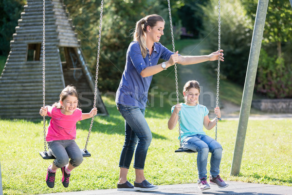 Family with two girls and mother on playground swing Stock photo © Kzenon