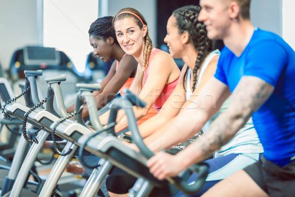 Side view of a beautiful woman smiling while cycling at the gym Stock photo © Kzenon