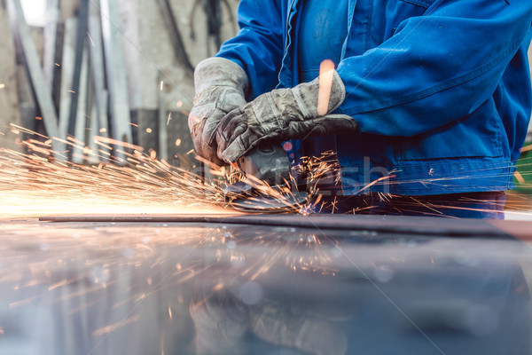 Worker in metal factory grinding workpiece with sparks flying Stock photo © Kzenon