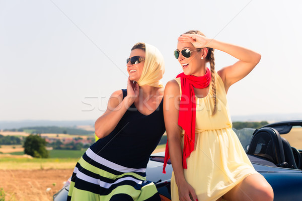 Two women sitting on hood of convertible car  Stock photo © Kzenon