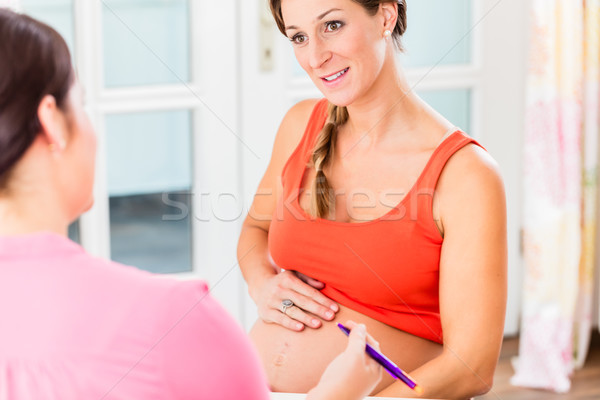 Expectant mother with her hand on pregnant belly consulting midw Stock photo © Kzenon