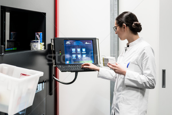 Stock photo: pharmacist using a computer while managing the drug stock