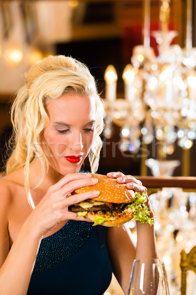 Young woman in fine restaurant, she eats a burger Stock photo © Kzenon