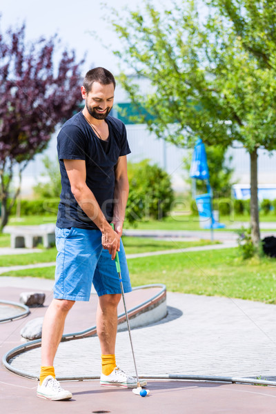 Férfi játszik miniatűr golf klub labda Stock fotó © Kzenon