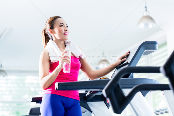Smiling woman on treadmill presenting water bottle Stock photo © Kzenon