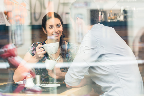 Young couple sitting at a table while drinking coffee and cappuc Stock photo © Kzenon