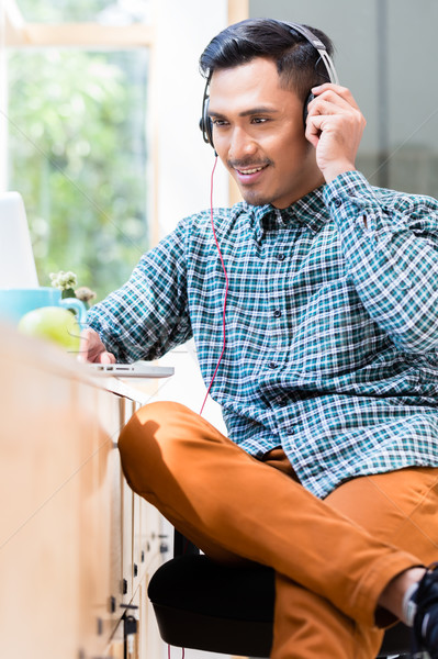 Stock photo: Young Asian man listening and watching an online video