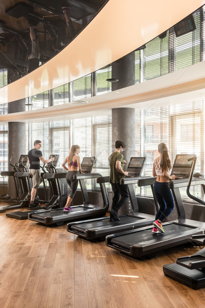 Group of four people running on treadmills in fitness gym Stock photo © Kzenon