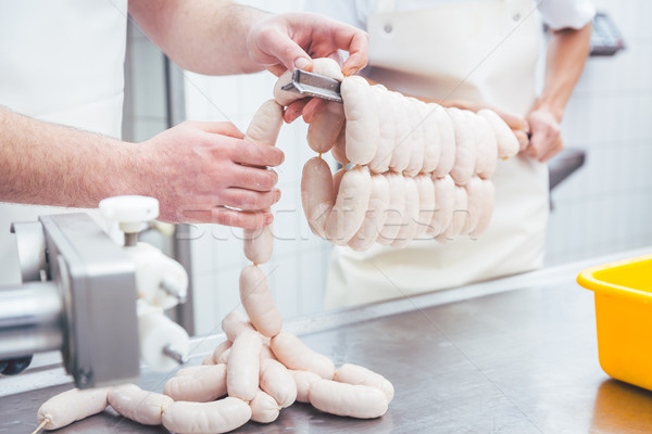 Worker working in butchery producing sausages putting them on beam Stock photo © Kzenon