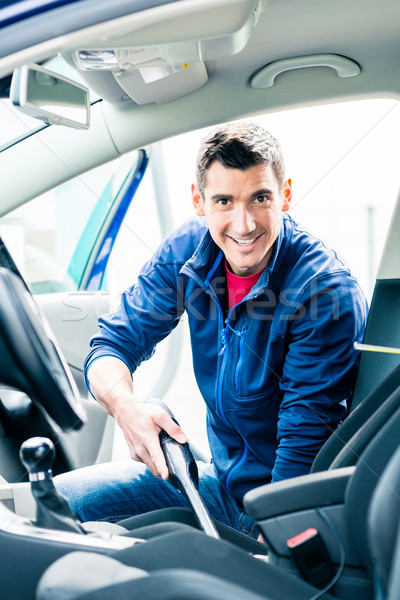 Young man using vacuum for cleaning the interior of a car  Stock photo © Kzenon