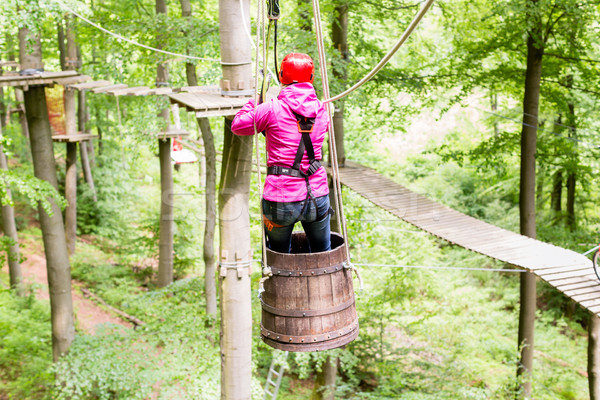 Woman sliding in barrel at high rope climbing course Stock photo © Kzenon