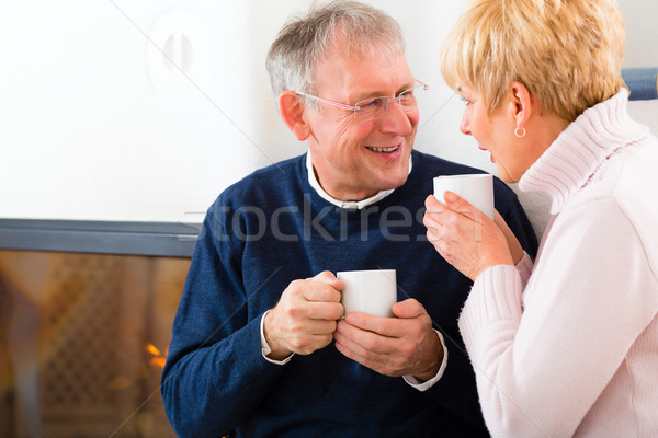 Seniors at home in front of fireplace with tea cup Stock photo © Kzenon