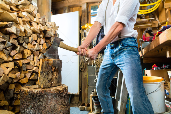 Young man chopping fire wood in mountain chalet Stock photo © Kzenon