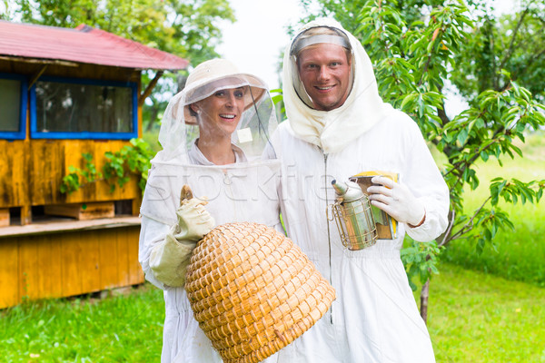 Stock photo: Beekeeper team working outdoor with smoker and beehive  