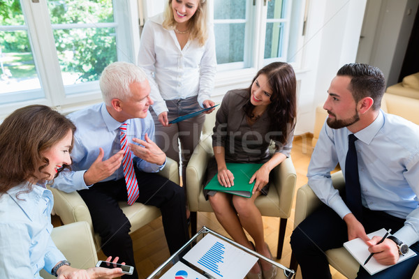 Five business people in team meeting studying graphs Stock photo © Kzenon