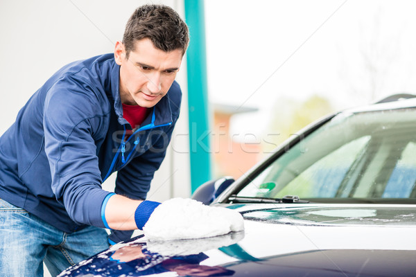 Hard-working man polishing car with white microfiber mitt Stock photo © Kzenon