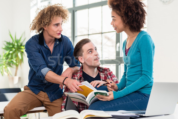 Three students comparing information from two different textbook Stock photo © Kzenon