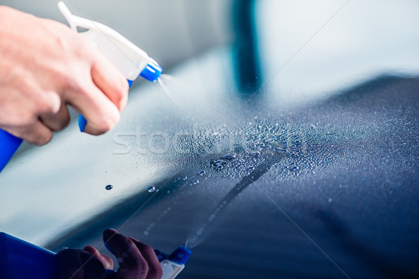 Hand spraying cleaning substance on the surface of a blue car Stock photo © Kzenon