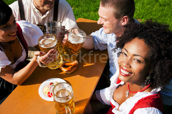 Group of four friends in beer garden eating and drinking Stock photo © Kzenon