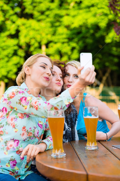 Friends taking selfie with smartphone in beer garden Stock photo © Kzenon
