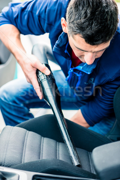 Young man using vacuum for cleaning the interior of a car  Stock photo © Kzenon